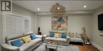 Brampton (Fletcher's Meadow) apartment for rent - A living room with a white couch, a chandelier, and a painting on the wall.