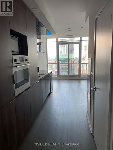Toronto (Bay Street Corridor) condo for rent - A modern kitchen with dark wood cabinets and stainless steel appliances.
