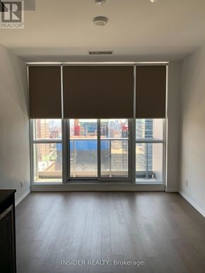 Toronto (Bay Street Corridor) condo for rent - A room with a large window and a view of a cityscape.