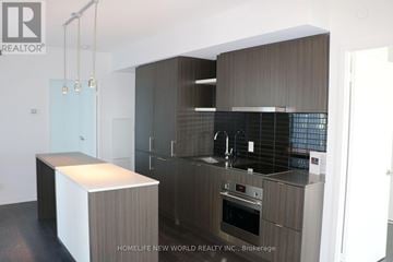 Toronto (Waterfront Communities) condo for rent - A modern kitchen with dark wood cabinets and a white island.