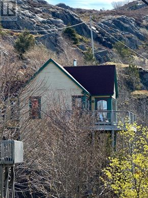 St. John's apartment for rent - A house with a green roof and a balcony is surrounded by trees and a mountain in the background.