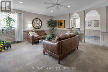 St. Catharines (Fairview) condo for rent - A living room with a brown leather couch and a ceiling fan.
