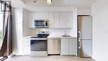 Brantford condo for rent - A kitchen with white cabinets and a stainless steel refrigerator.