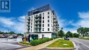 Brantford condo for rent - A modern apartment building with a parking lot in front.