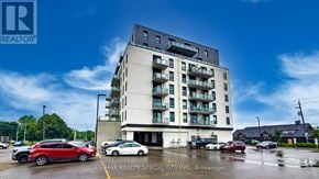 Brantford condo for rent - A multi-story building with a parking lot in front of it.
