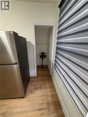 Brantford apartment for rent - A stainless steel refrigerator sits in a kitchen next to a wall with horizontal slats.