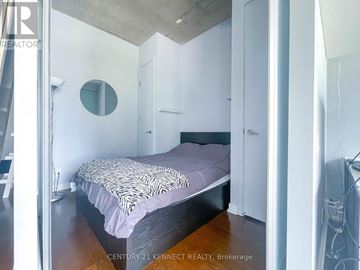 Toronto (Waterfront Communities) condo for rent - A bedroom with a bed and a round mirror on the wall.