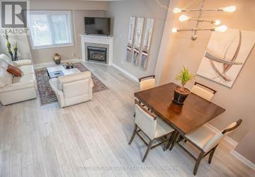 Toronto (Niagara) townhouse for rent - A well-lit living room with a fireplace and a dining table set for four.