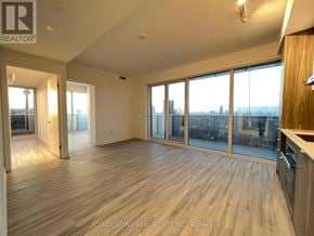Toronto (Waterfront Communities) condo for rent - A spacious room with wooden flooring and large windows overlooking a cityscape.