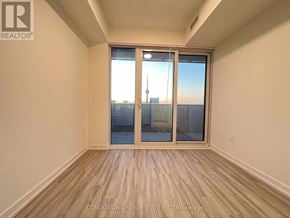 Toronto (Waterfront Communities) condo for rent - A room with a view of a city skyline through a sliding glass door.