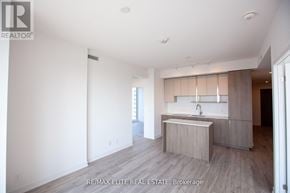 Toronto (Willowdale East) condo for rent - A spacious, empty room with a kitchenette and a window.