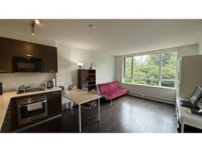 Surrey apartment for rent - A kitchen with a microwave, oven, and a table with a red couch.