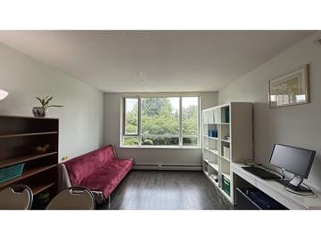 Surrey apartment for rent - A living room with a red couch and a desk with a computer monitor.