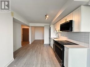 Pickering (Bay Ridges) condo for rent - A kitchen with white cabinets and a black countertop.