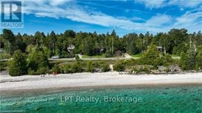 Northern Bruce Peninsula apartment for rent - A beachfront property with a clear blue sky and a few trees in the background.