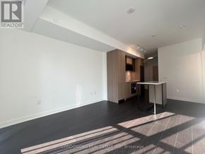 Toronto (Regent Park) condo for rent - A spacious, empty room with a kitchenette in the corner.