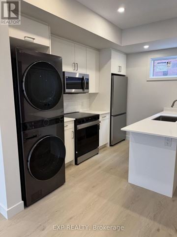 Ottawa multi-family for rent - A modern kitchen with a washer and dryer built into the cabinetry.