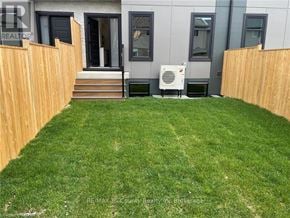 Tillsonburg condo for rent - A backyard with a wooden fence and a well-maintained lawn.
