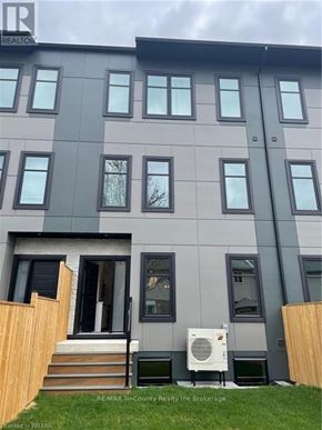 Tillsonburg condo for rent - A grey building with a black door and windows.