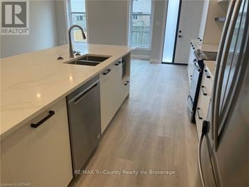 Tillsonburg condo for rent - A kitchen with a sink, refrigerator, and cabinets.