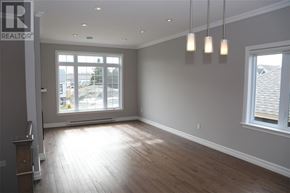 St. John's apartment for rent - A large empty room with wooden floors and a window overlooking a parking lot.