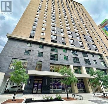 Ottawa condo for rent - A tall building with a grey facade and a sign that says "REALTOR" in front of it.