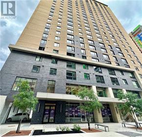 Ottawa condo for rent - A tall building with a grey facade and a sign that says "REALTOR" in front of it.