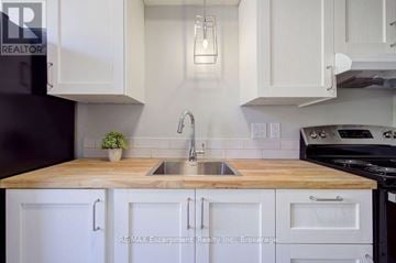 Burlington (Brant) multi-family for rent - A kitchen with white cabinets and a wooden countertop.