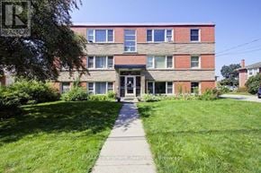 Burlington (Brant) multi-family for rent - A red brick building with a green lawn in front.