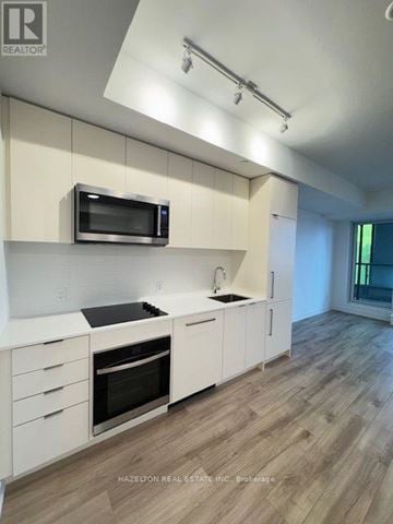 Toronto (Willowdale East) condo for rent - A modern kitchen with white cabinets and a microwave above the stove.