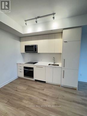 Toronto (Willowdale East) condo for rent - A kitchen with white cabinets and a black microwave.