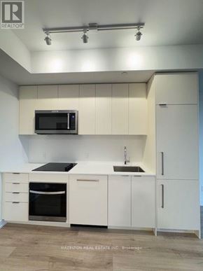 Toronto (Willowdale East) condo for rent - A modern kitchen with white cabinets and a microwave above the stove.