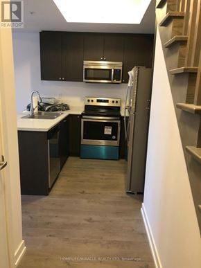 Pickering (Town Centre) townhouse for rent - A kitchen with a stove top oven and a microwave above it.