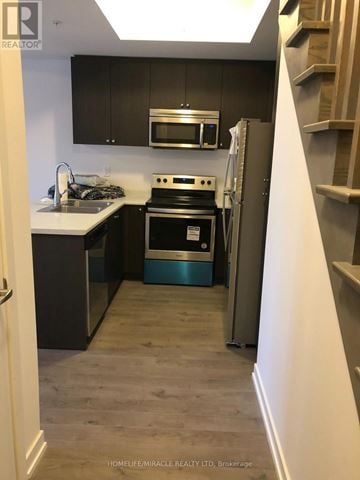 Pickering (Town Centre) townhouse for rent - A kitchen with a stove top oven and a microwave above it.