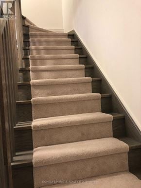 Pickering (Town Centre) townhouse for rent - A staircase with beige carpeted steps and dark wood balusters.