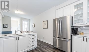 Centre Wellington (Fergus) townhouse for rent - A kitchen with white cabinets and a stainless steel refrigerator.