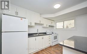 St. Catharines (Burleigh Hill) apartment for rent - A kitchen with white cabinets and a white fridge.