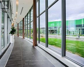 Toronto (Bayview Village) condo for rent - A long hallway with lots of windows and a potted plant.