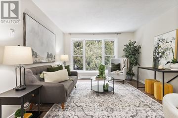 Cobourg condo for rent - A living room with a grey couch, a coffee table, and a large window.