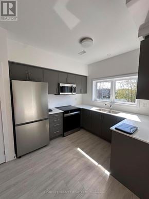 Guelph (Clairfields/Hanlon Business Park) townhouse for rent - A kitchen with a refrigerator, microwave, and sink.