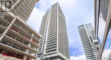 Toronto (Niagara) condo for rent - A tall building with a glass facade stands in front of a partly cloudy sky.