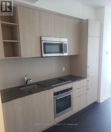 Toronto (Niagara) condo for rent - A kitchen with a microwave oven mounted above a stove.