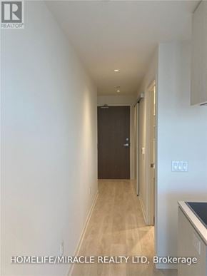 Toronto (Waterfront Communities) condo for rent - A hallway with a door on the left and a kitchen area on the right.