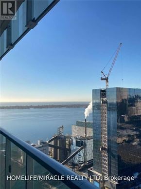 Toronto (Waterfront Communities) condo for rent - A view from a high-rise building looking out over a body of water with a crane in the distance.