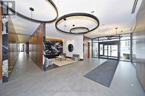 Vaughan (Concord) condo for rent - A modern living room with a large circular light fixture and a black couch.