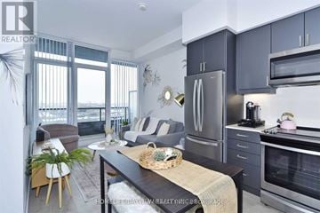Vaughan (Concord) condo for rent - A modern kitchen with stainless steel appliances and a dining table with chairs.