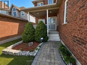 Kitchener apartment for rent - A house with a brick wall and a small garden in front.