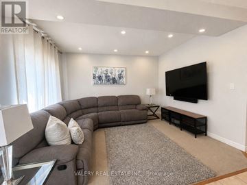 Kitchener apartment for rent - A living room with a grey sofa and a flat screen TV mounted on the wall.