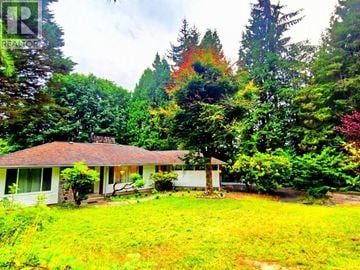 West Vancouver apartment for rent - A house with a white porch and a brown roof is surrounded by trees.