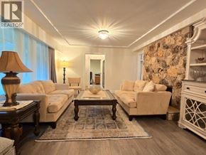 West Vancouver apartment for rent - A well-lit living room with a large sofa, a coffee table, and a side table with a lamp.